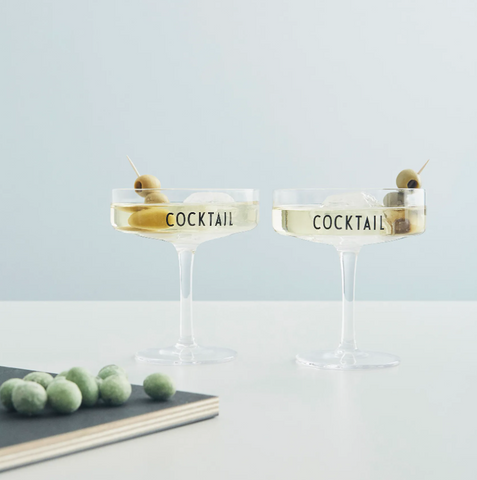 Cocktailglas wo "Cocktail" in Schwarz drauf steht mit Martinis befüllt