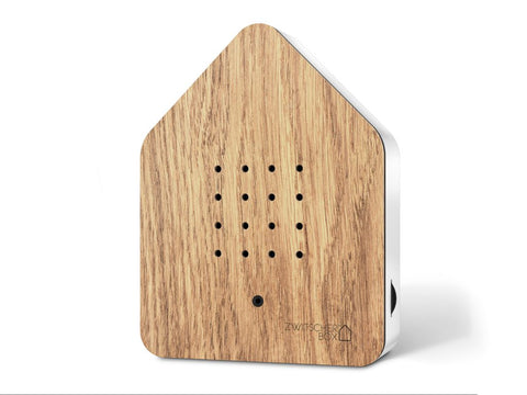 Zwitscherbox in Form eines Hauses mit hellbrauner Holzverkleidung, Lautsprecher auf der Vorderseite