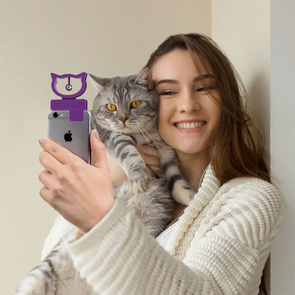 Frau mit Katze macht ein Selfie, auf ihrem Handy violettes CatSelfie Tool mit Glocke