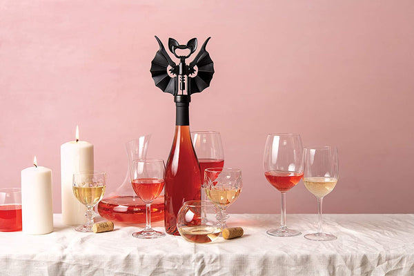 Fledermaus Korkenzieher in Anwendung auf einem gedeckten Tisch mit Weinflasche und Weinglaesern